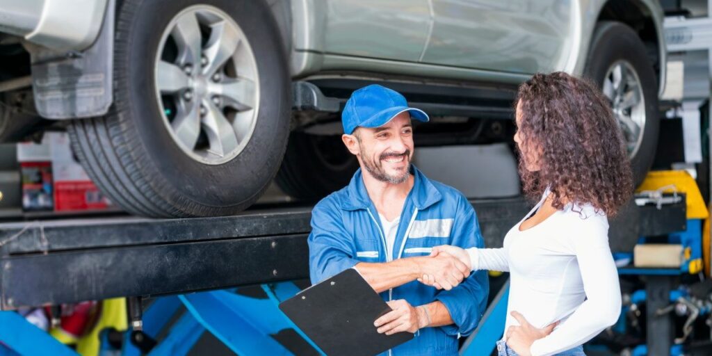 mechanic talking with client beside a lifted vehicle for repair