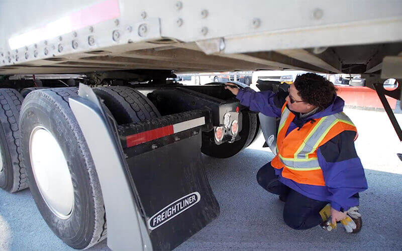 Professional inspector checking the wheels and breaks of a trailer truck