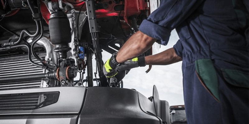 mechanic turning screws and checkingt he underside of the trailer truck